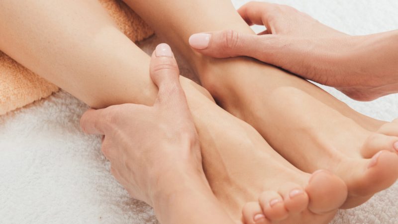 panoramic shot of masseur doing foot massage to adult woman in spa