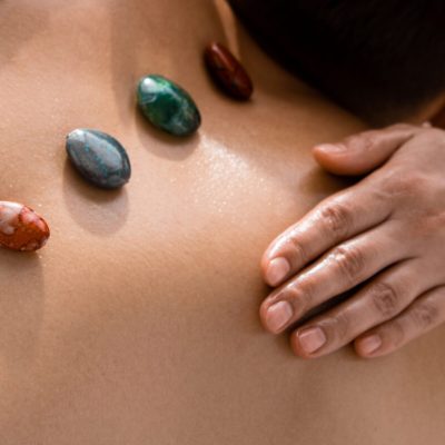 panoramic shot of masseur and shirtless man with stones on back