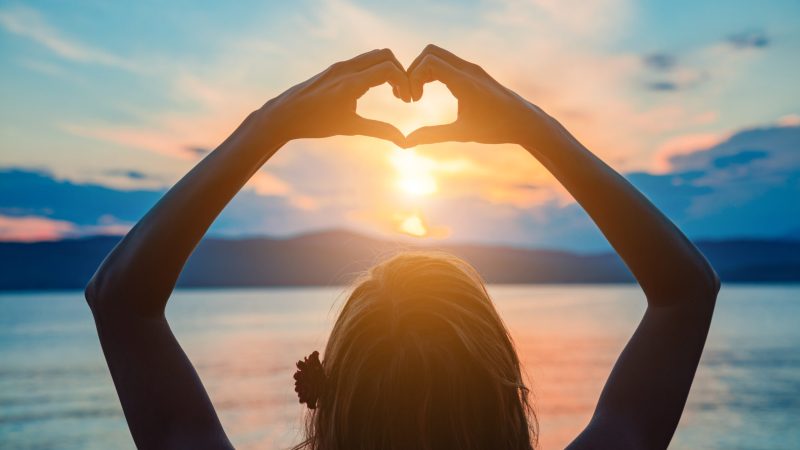Woman with heart shaped sign enjoying ocean tropical time.